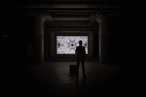 A man stands in front of an art installation that combines art and science.